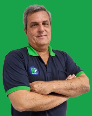Foto profissional de Rogério Formigoni, instrutor especialista em sistemas ARLA 32 e pós-tratamento Euro 6, homem de cabelos grisalhos com braços cruzados, uniforme polo azul-marinho com detalhes verdes e logo RF Treinamentos, fundo verde vibrante, retrato em estúdio, expressão confiante